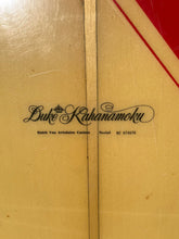 Load image into Gallery viewer, Close-up of a product with 'Duke Kahanamoku' branding on a beige background.