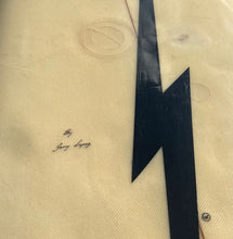 Load image into Gallery viewer, A close-up of a beige fabric surface with a large black lightning bolt graphic and small cursive text reading 'By Gerry Lopez'.