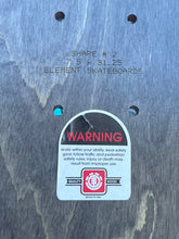 Load image into Gallery viewer, Close-up of the underside of a wooden skateboard deck showing stamped dimensions, pre-drilled holes, and a white warning label with the Element Skateboards logo.