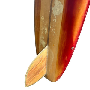 Close-up of a surfboard with a red and wooden design on a white background