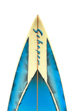Load image into Gallery viewer, Close-up of the nose of a surfboard with a cream-colored top sheet, blue painted side panels, and the brand name 'Schaper' written in blue script.