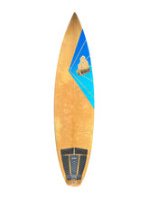 Load image into Gallery viewer, A Al Merrick surfboard with a natural wood grain top, a blue and gold graphic on the nose, and black grip pads on the tail, shown against a plain white background.