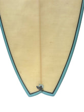 Load image into Gallery viewer, Close-up of the tail section of a surfboard with a natural light hemp body and a teal outline around the edge, shown against a white background.