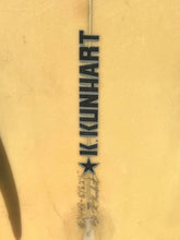 Load image into Gallery viewer, Close-up of a yellow surfboard showing the vertical K. Kunhart logo printed in black, with a star symbol and small model text near the fin.