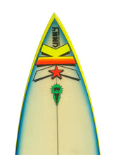 Load image into Gallery viewer, A close-up studio shot of the nose section of a surfboard against a white background. The board features a cream-colored base with a blue gradient along the sides, a bright yellow edge, and a graphic design including a yellow 'K' with red and orange stripes, a red star, and a green shark logo.