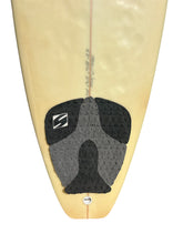 Load image into Gallery viewer, A close-up of the tail section of a surfboard showing a black and gray traction pad with a white stylized 'S' logo, on a pale yellow board against a white background.