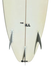 Load image into Gallery viewer, Close-up of the tail section of a cream-colored surfboard with three gray fins and black text reading 'THE ill' and 'Grass' near the bottom, shown against a white background.