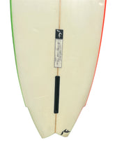 Load image into Gallery viewer, Close-up of the tail section of a surfboard with a cream base, green edge striping on the left, red edge striping on the right, a black fin, and a central sticker label.