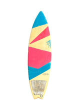 Load image into Gallery viewer, A surfboard with a colorful geometric pattern of yellow, pink, and blue, featuring a textured grip pad on the tail.