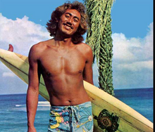 Load image into Gallery viewer, Tiger Espere holding a surfboard by the ocean